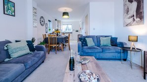 Ein modernes Wohnzimmer mit zwei Sofas, einem Esstisch und einer Küche im Hintergrund.