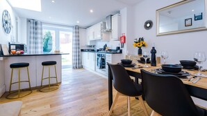 A modern kitchen with a dining area, bar stools, and a large mirror. - Stunning Home Perfect for Groups Free Parking (Chester)