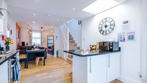 A modern kitchen with a central island, a dining area with a sofa, and a staircase leading to an upper level. - Stunning Home Perfect for Groups Free Parking (Chester)