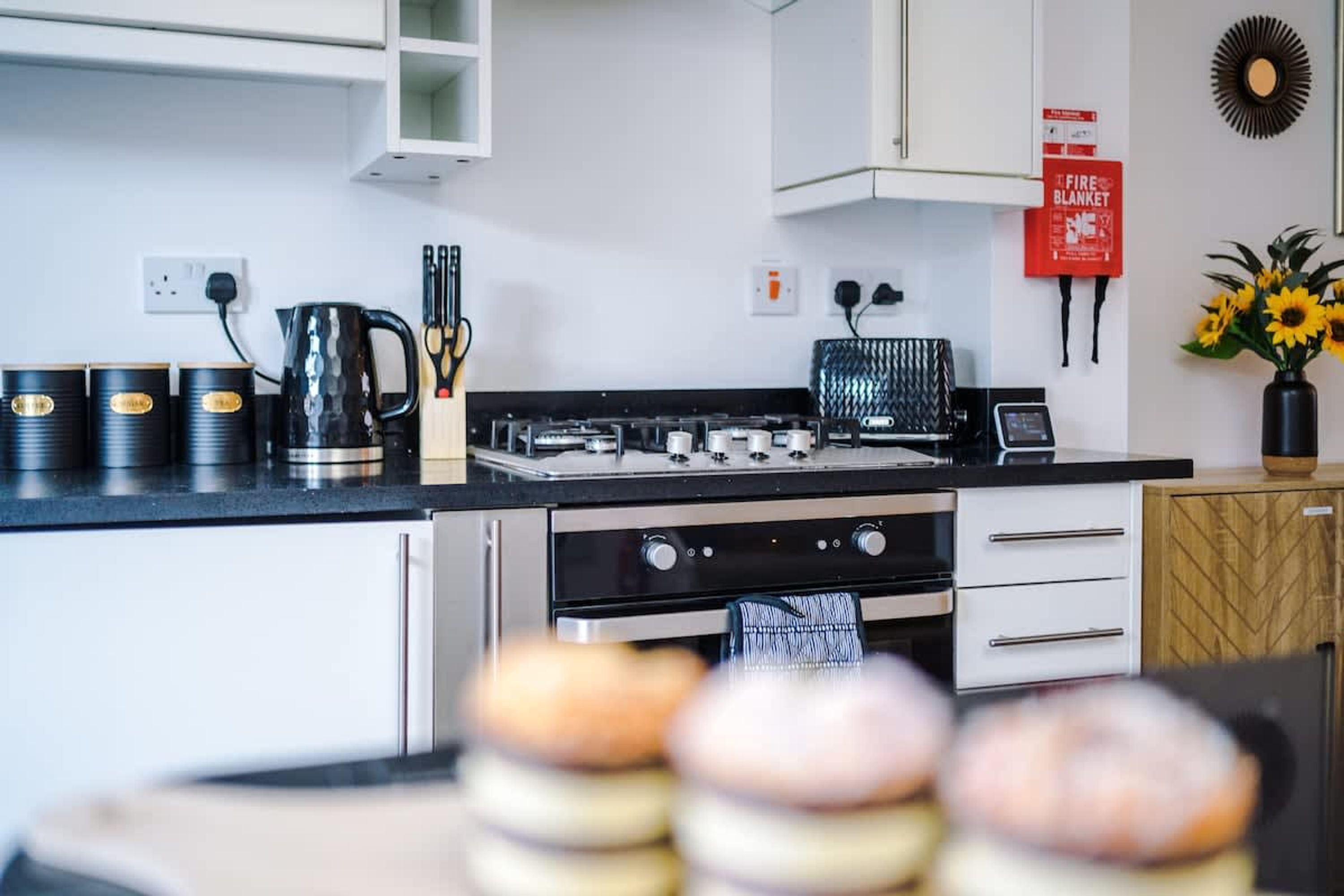 A modern kitchen with stainless steel appliances, a coffee maker, and a fire blanket sign.
