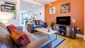 A modern living room with a sofa, coffee table, and a TV displaying 'NETFLIX'. - Stunning Home Perfect for Groups Free Parking (Chester)