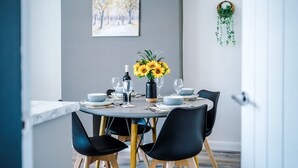 Una mesa de comedor dispuesta con platos, vasos y un florero de girasoles.