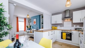 A modern kitchen with white cabinets, a wooden countertop, and a yellow towel hanging on the oven. - Stylish Home Incredible Location Sleeps 5 (Chester)