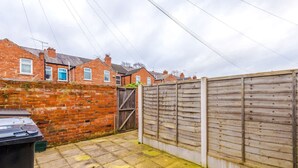 A residential area with brick houses, a wooden fence, and a paved driveway. - Modern Apartment Ideal for Business Sleeps 3 (Crewe)