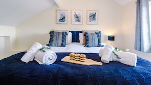Ein Hotelzimmer mit einem Bett, Handtüchern, einer Auswahl an Gebäck und drei gerahmten Bildern an der Wand.