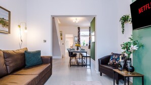 A modern living room with a sofa, a coffee table, and a TV mounted on the wall. - Stunning 3-bed House Amazing Location Sleeps 5 (Nantwich)