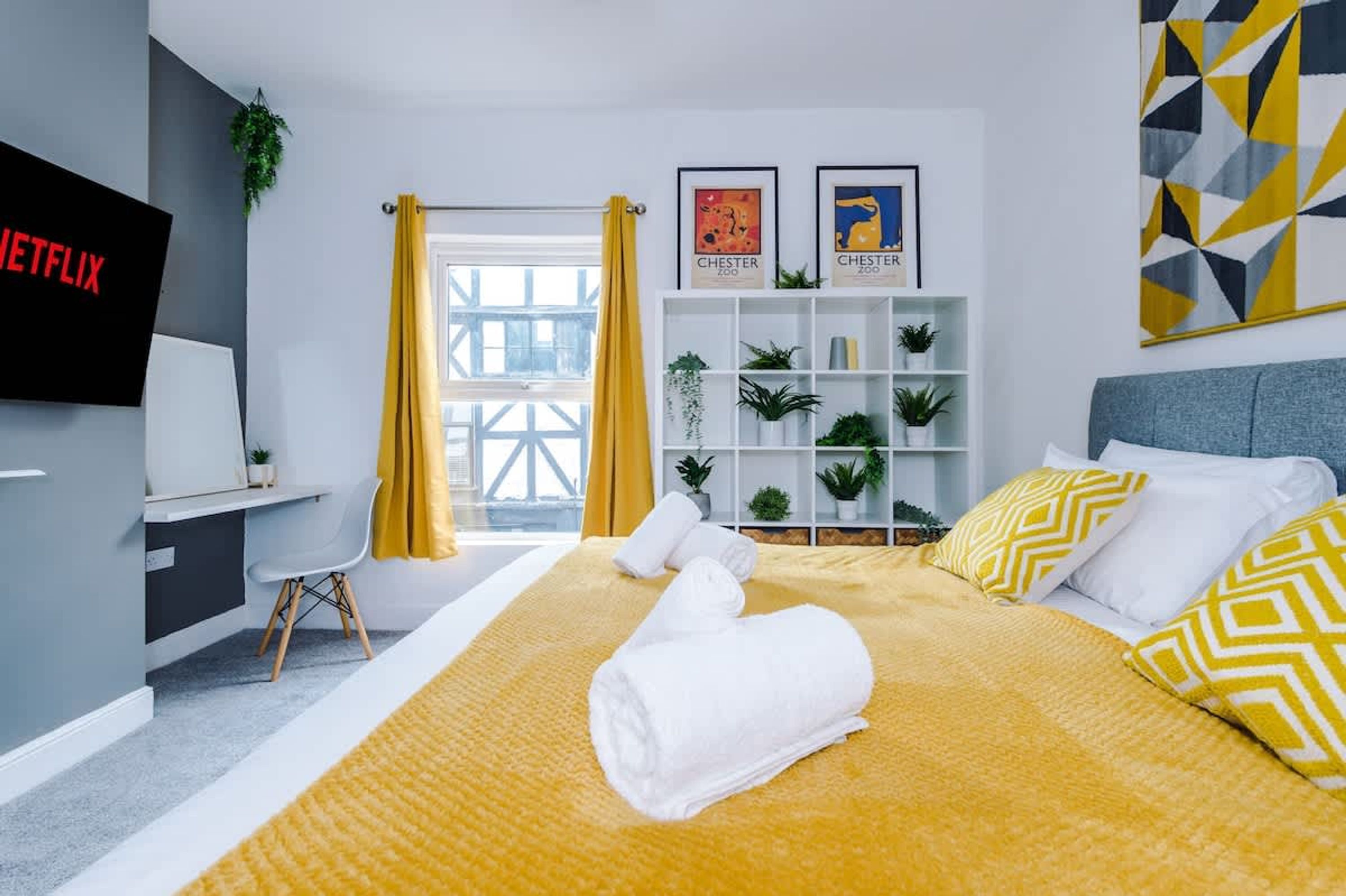 Una habitación de hotel moderna con una cama, un escritorio, un televisor y una estantería.