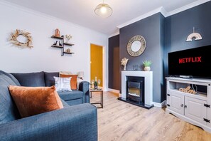 Ein Wohnzimmer mit Kamin, Fernseher und Bücherregal.