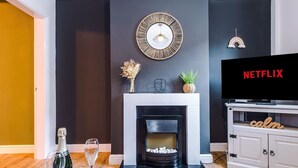 Una sala de estar con chimenea, televisor y una botella de champán.