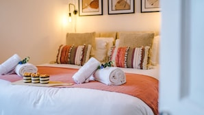 A neatly made bed with rolled towels and a tray of snacks, a wall-mounted light, and framed artwork. - Lovely House Great Location Perfect for Couples (Chester)