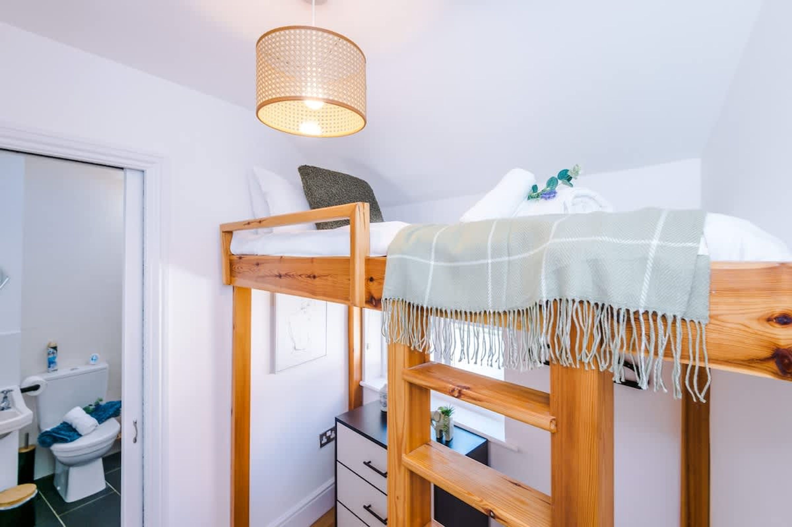 En køjeseng med træramme, en hængende lampe og et vindue med udsigt.
