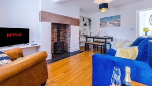 A living room with a fireplace, a TV, a sofa, a dining area, and a blue couch. - Lovely House Great Location Perfect for Couples (Chester)