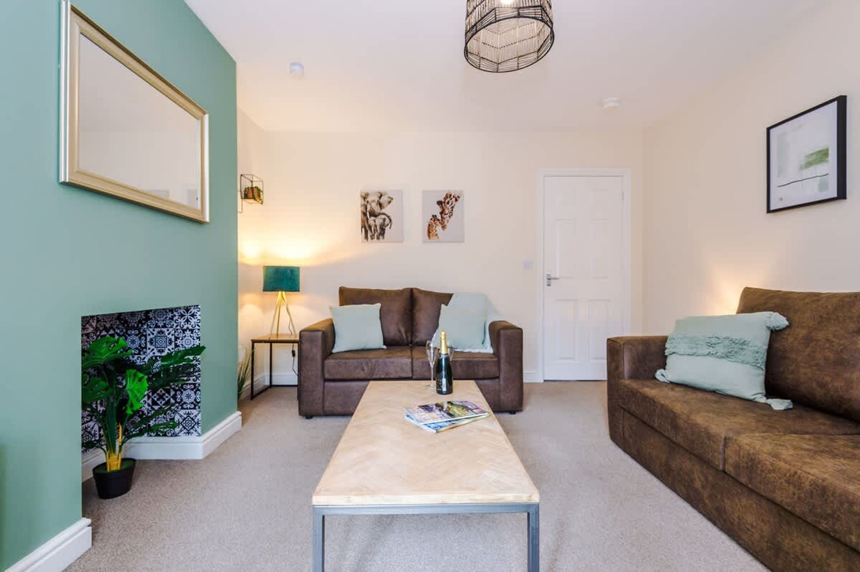 A living room with two brown sofas, a coffee table, a lamp, and framed pictures on the walls.