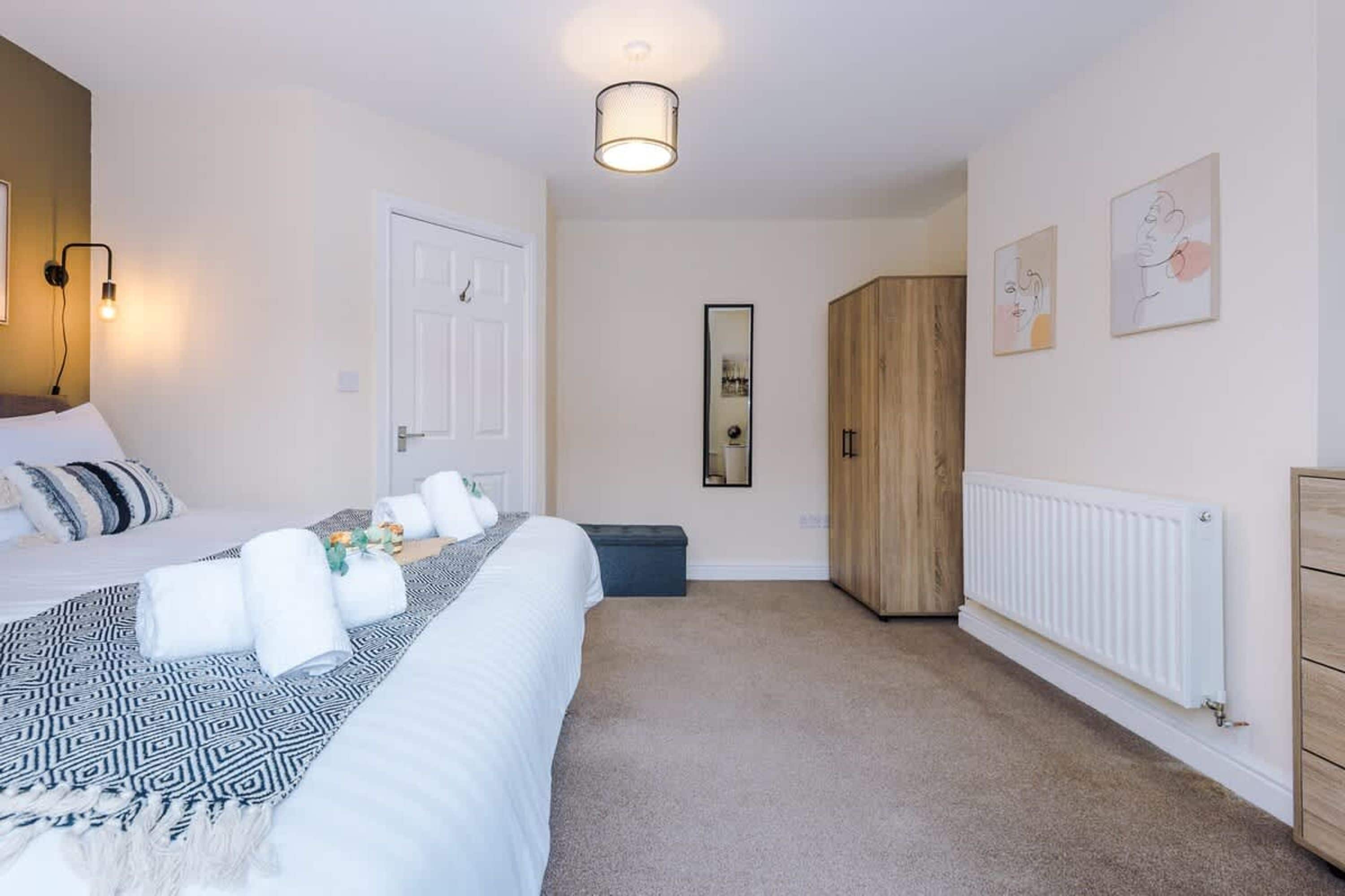 A bedroom with a bed, bedside tables, a wardrobe, a mirror, and a radiator.