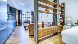 A modern kitchen with a built-in stove, a dining area with a wooden table and chairs, and a living room with a sofa and a coffee table. - Pristine Studio Incredible Location Long Stays (London)