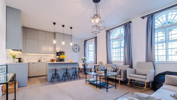 A modern interior with a kitchen, dining area, and living room, featuring contemporary furniture and large windows. - New Stylish City-centre Flat w Parking Sleeps 4 (Birmingham)