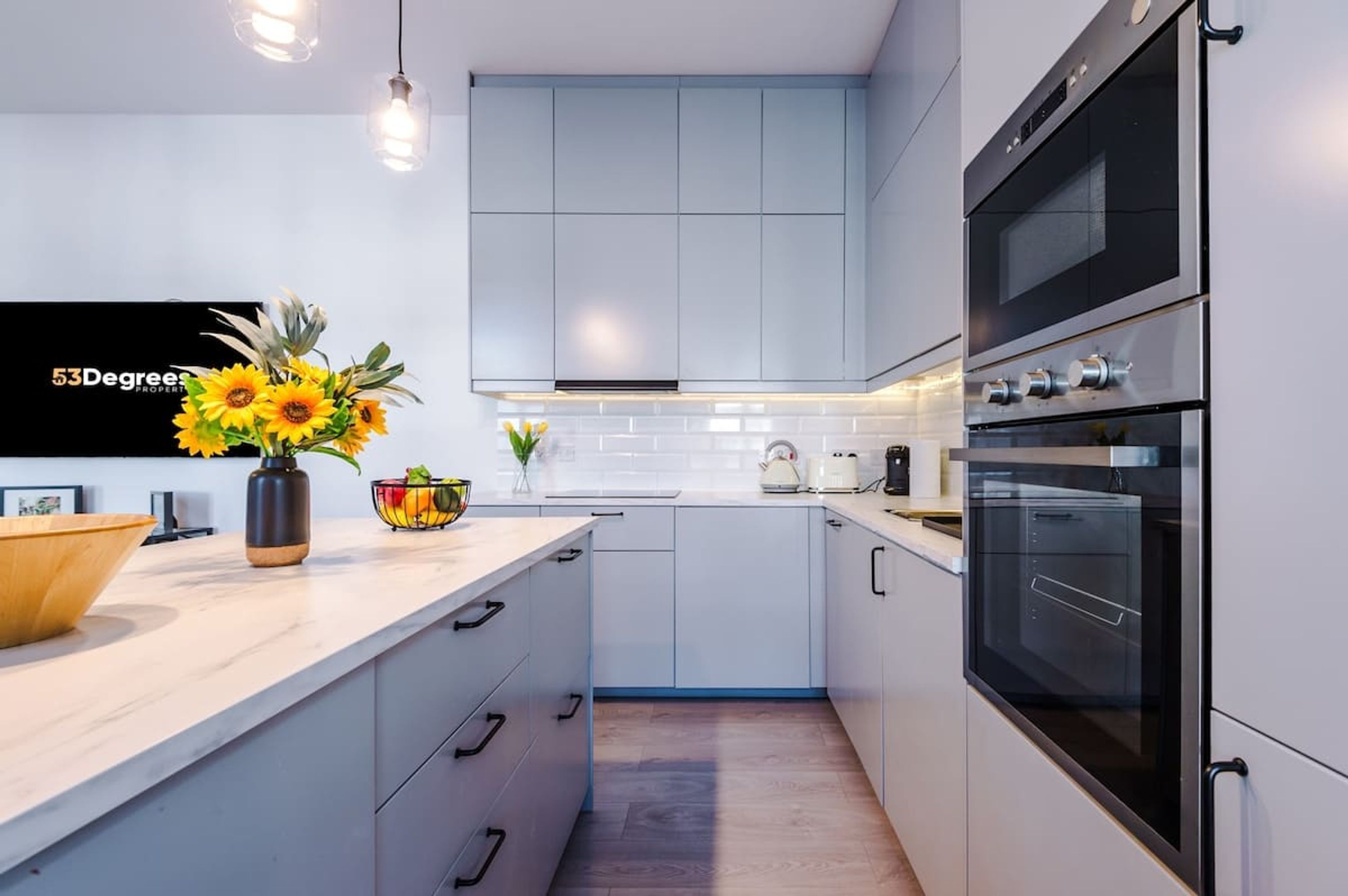 Una cocina moderna con armarios blancos, un horno grande y una encimera con un jarrón de girasoles.
