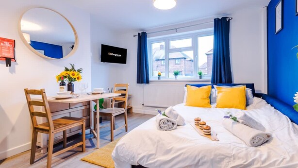 Ein Hotelzimmer mit Bett, Schreibtisch, Stuhl, Fernseher und einem Fenster mit Vorhängen.