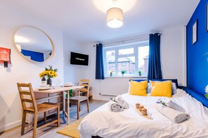 Une chambre d’hôtel avec un lit, un bureau, une chaise, une télévision et une fenêtre avec des rideaux.