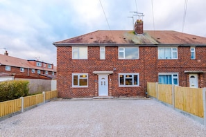 A two-story brick house with a white door, multiple windows, and a gravel driveway. - NEW Spacious Apartment Ideal for Business Work (Crewe)