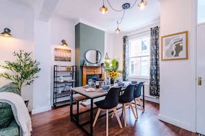 A dining area with a wooden table, black chairs, a vase with sunflowers, a mirror, and a bookshelf. - NEW Stylish City Centre Home Great Location (Chester)