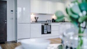 A modern kitchen with white cabinetry, a built-in oven, and a visible door handle. - NEW Stylish Apartment Amazing Location Sleeps 4 (Manchester)