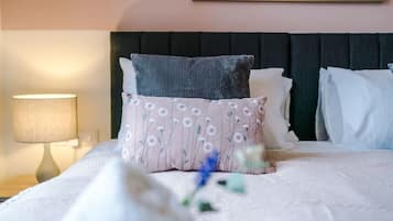 A neatly made bed with a pillow, a bedside lamp, and a framed picture on the wall.
