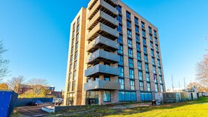 A multi-story building with a modern architectural design, featuring balconies and large windows. - NEW Pristine 2-bed Flat Great Location Sleeps 6 (Liverpool)