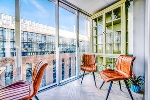 A balcony with large windows, two chairs, and a green cabinet. - NEW Pristine Apartment City Centre Amazing Views (London)