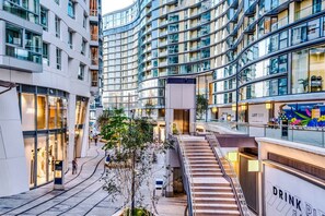 A modern urban building with multiple floors, glass facades, and a central atrium with a staircase. - NEW Pristine Apartment City Centre Amazing Views (London)