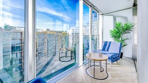A modern living room with large windows, a sofa, a small table, and a potted plant. - NEW Pristine Apartment City Centre Amazing Views (London)