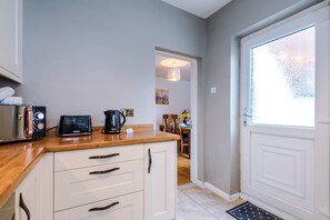A kitchen with a wooden countertop, white cabinets, a coffee maker, and a kettle. - Stunning Home Amazing Location Great For Groups (Chester)