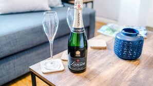 A bottle of champagne, a glass, and a blue vase on a wooden table. - Stunning Home Amazing Location Great For Groups (Chester)