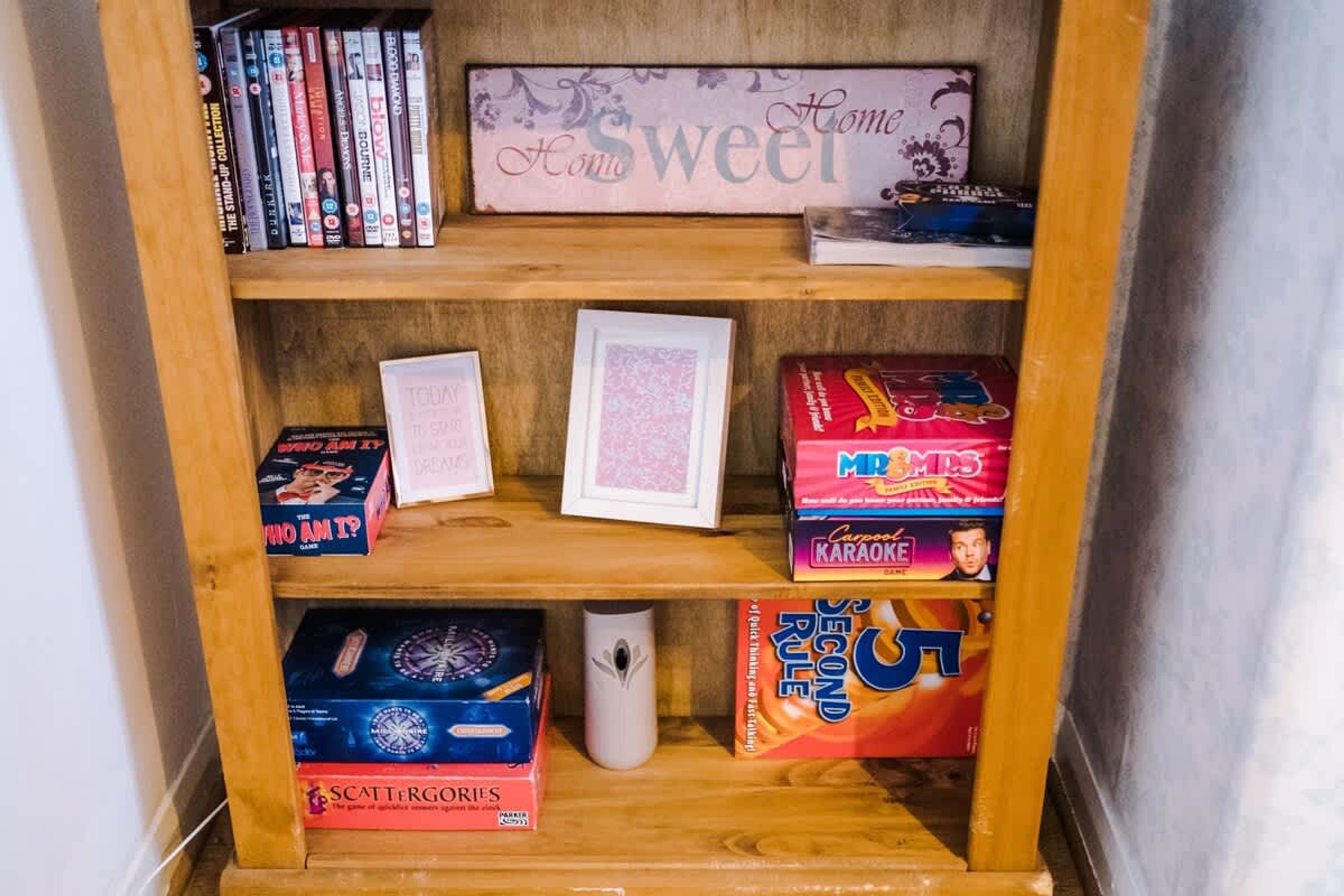 A wooden shelf with various board games and a framed picture.