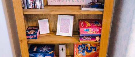 A wooden shelf with various board games and a framed picture.
