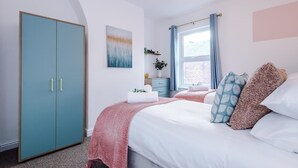 Une chambre à coucher comprenant un lit, une armoire, une fenêtre avec des rideaux et une œuvre d’art accrochée au mur.