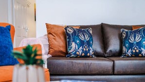 Un canapé en cuir marron agrémenté de coussins à motifs, une petite plante et un coussin rayé.