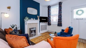 Un salon avec une cheminée, un téléviseur, un canapé et un fauteuil.