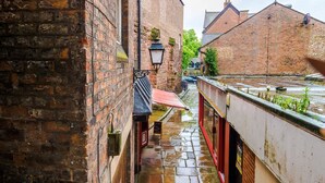 Un callejón estrecho con edificios de ladrillo, un toldo rojo y una barandilla de metal.