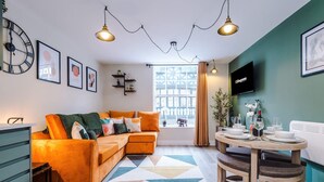 A modern living room with a sofa, a dining table, and a TV. - NEW Stylish 1-bed Flat Great Location Sleeps 4 (Chester)