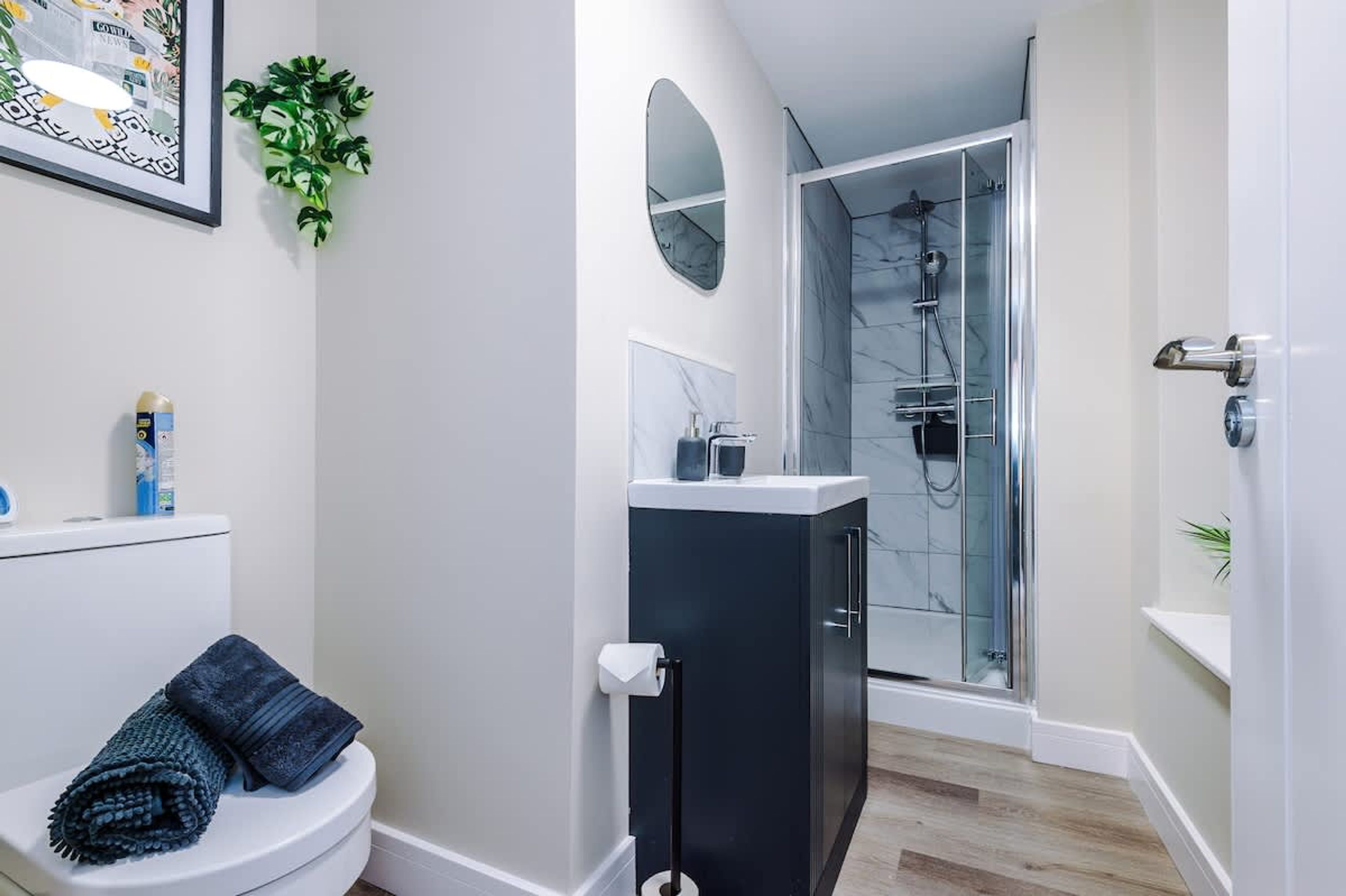 A modern bathroom with a toilet, a shower enclosure, and a sink.