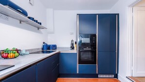 A modern kitchen with blue cabinets, a microwave, an oven, and a fruit bowl on the counter. - Charming Home Perfectly Located in Chester (Chester)
