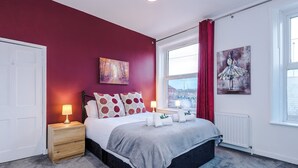 A bedroom with a bed, nightstand, lamp, window, and artwork. - Charming Home Perfectly Located in Chester (Chester)