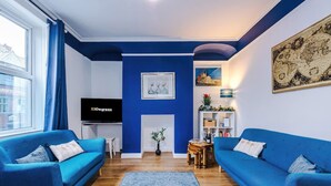 A living room with two blue sofas, a TV, a fireplace, and a bookshelf. - Charming Home Perfectly Located in Chester (Chester)