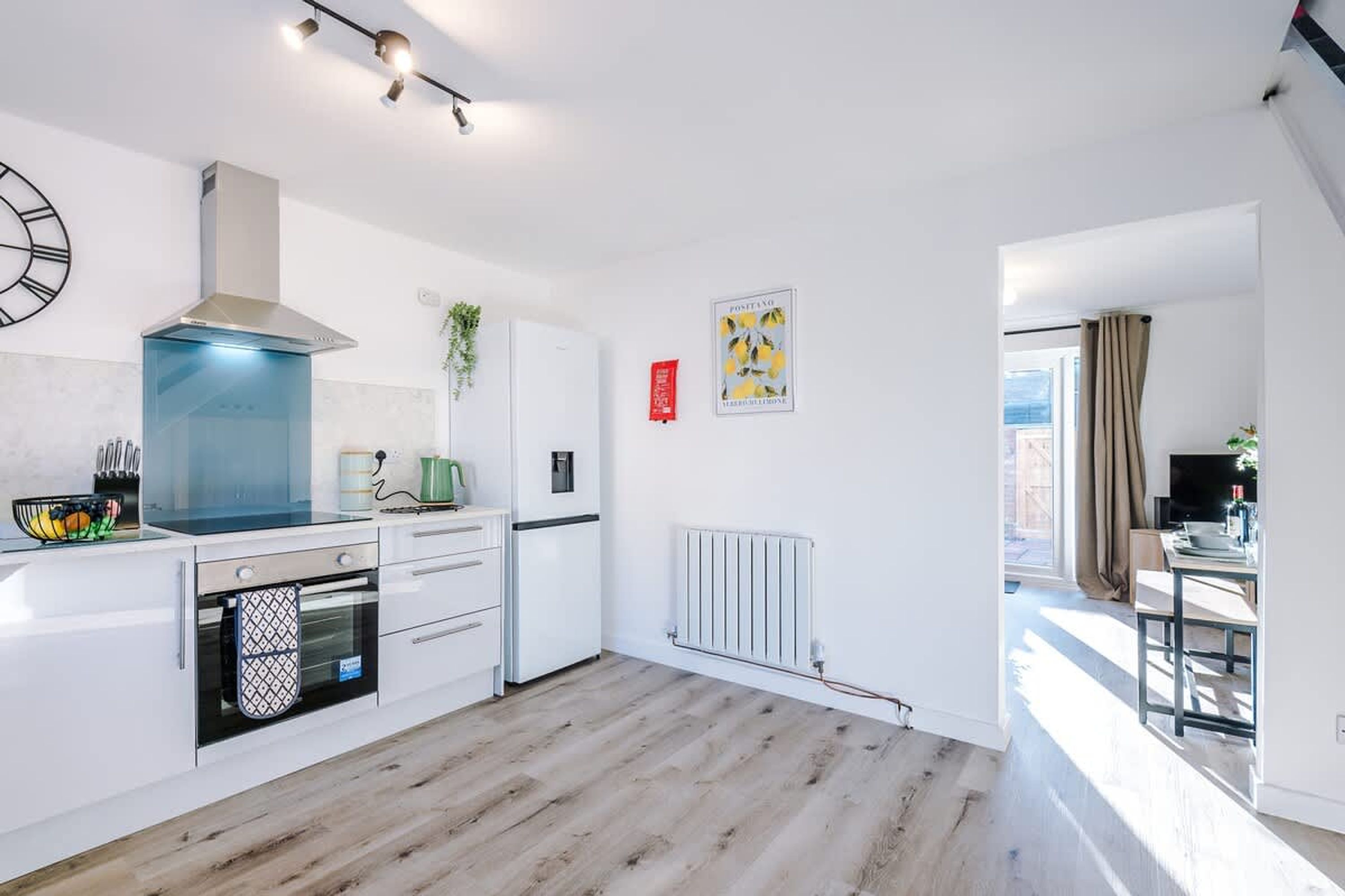 Eine moderne Küche mit Einbauofen, Dunstabzugshaube aus Edelstahl und einem weißen Kühlschrank.