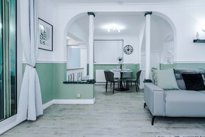 Um interior moderno com área de refeições, um sofá e um relógio na parede.