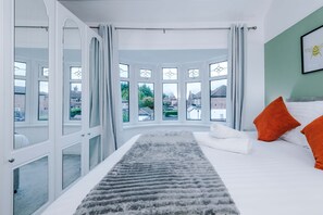 Quarto com uma cama grande, vista exterior e janela com cortinas.