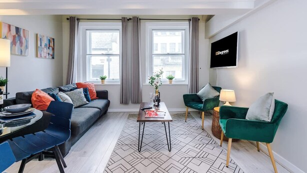 A modern living room with a sofa, chairs, a coffee table, and a TV. - City Centre Flat Perfect for Groups Weekends (Liverpool)