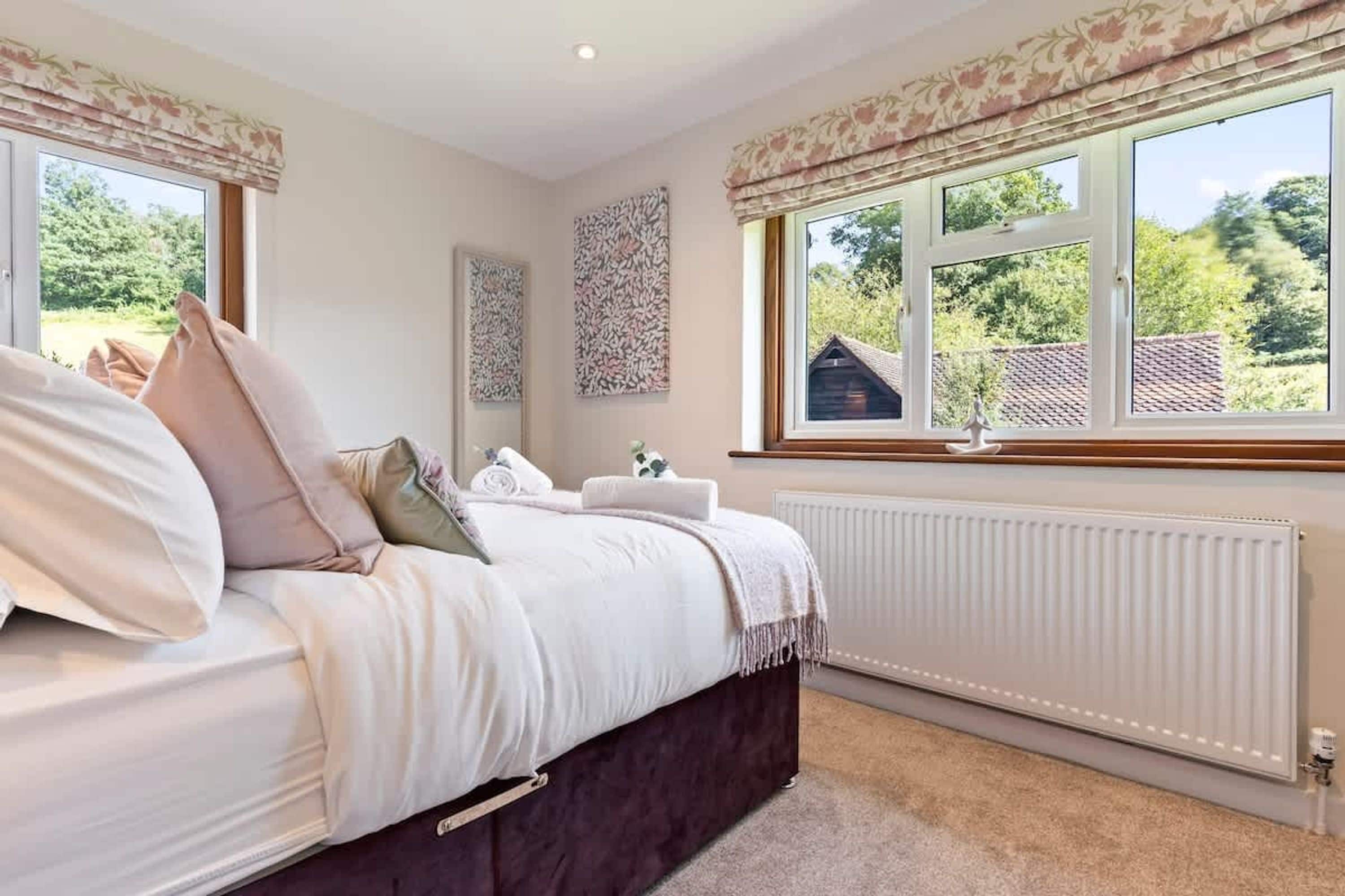 A bedroom with a bed, a radiator, and a window with a view of greenery.