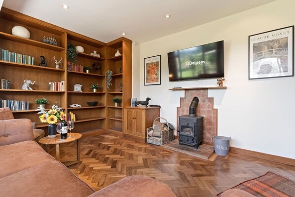 A cozy living room with a fireplace, bookshelves, a television, and a sofa. - Incredible Countryside Getaway With Tennis Court (Godalming)